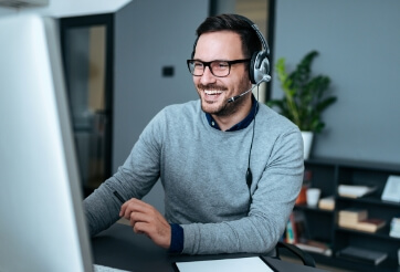 Smiling Man with Headset Looking at Monitor